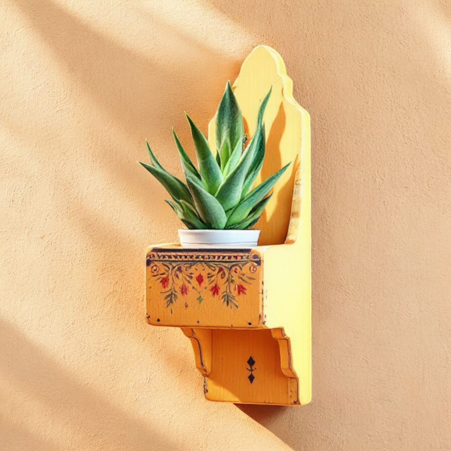 Hand-painted yellow wooden wall shelf with intricate multicolored designs, mounted on a textured wall with a potted plant.