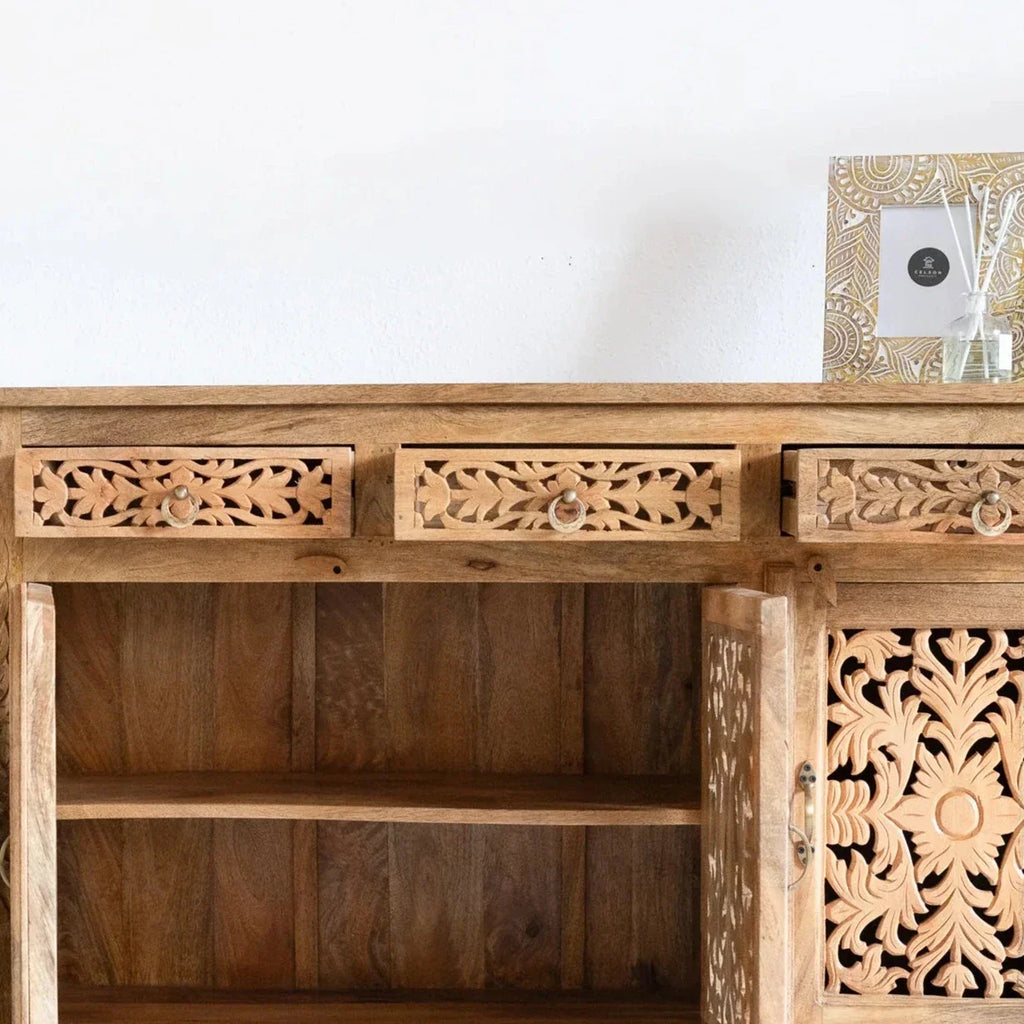 hand carved sideboard, mango wood sideboard, natural finish sideboard, floral carved sideboard, openwork sideboard, 3 door sideboard, 3 drawer sideboard, buffet sideboard, indian carved furniture, storage sideboard, dining room buffet, living room sideboard, entryway sideboard, statement sideboard, medium sideboard, handmade sideboard, artisan made sideboard, premium wood buffet, quality wood furniture, durable sideboard, sturdy buffet, timeless sideboard, elegant buffet, heirloom buffet, rustic sideboard, 