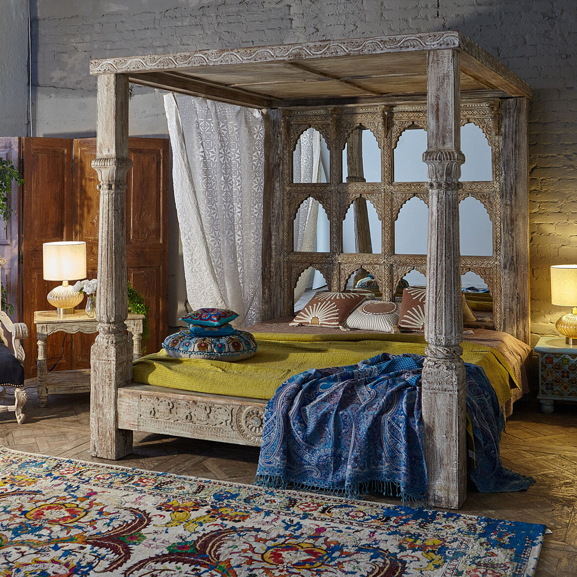 Wooden four-poster bed in a bedroom with decorative pillows and a blue throw blanket.