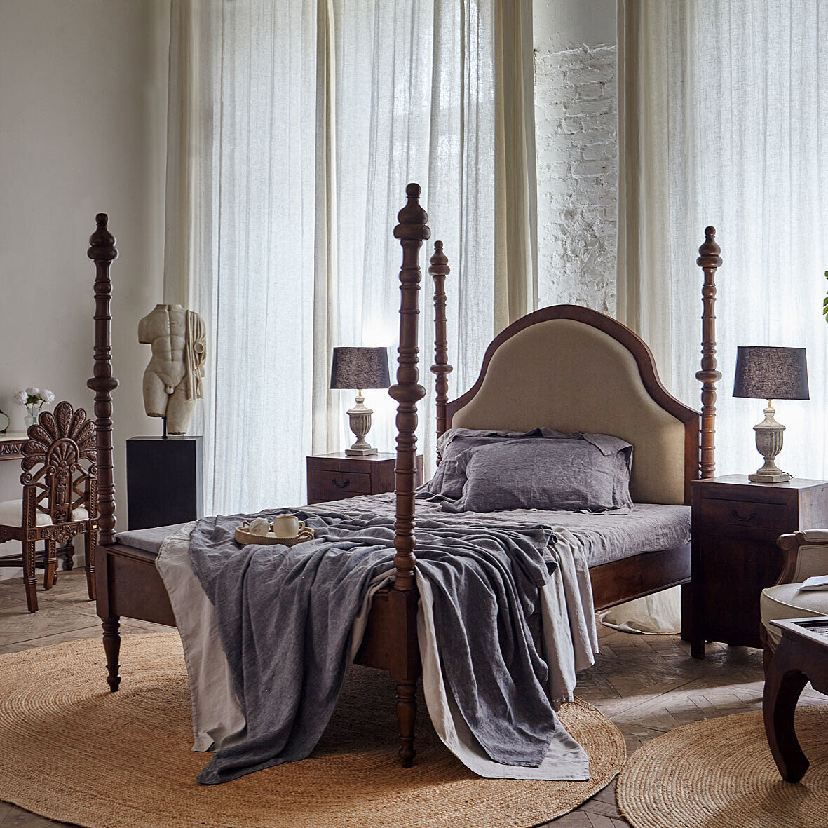 Bedroom with wooden bed, gray bedding, and lamps on nightstands.