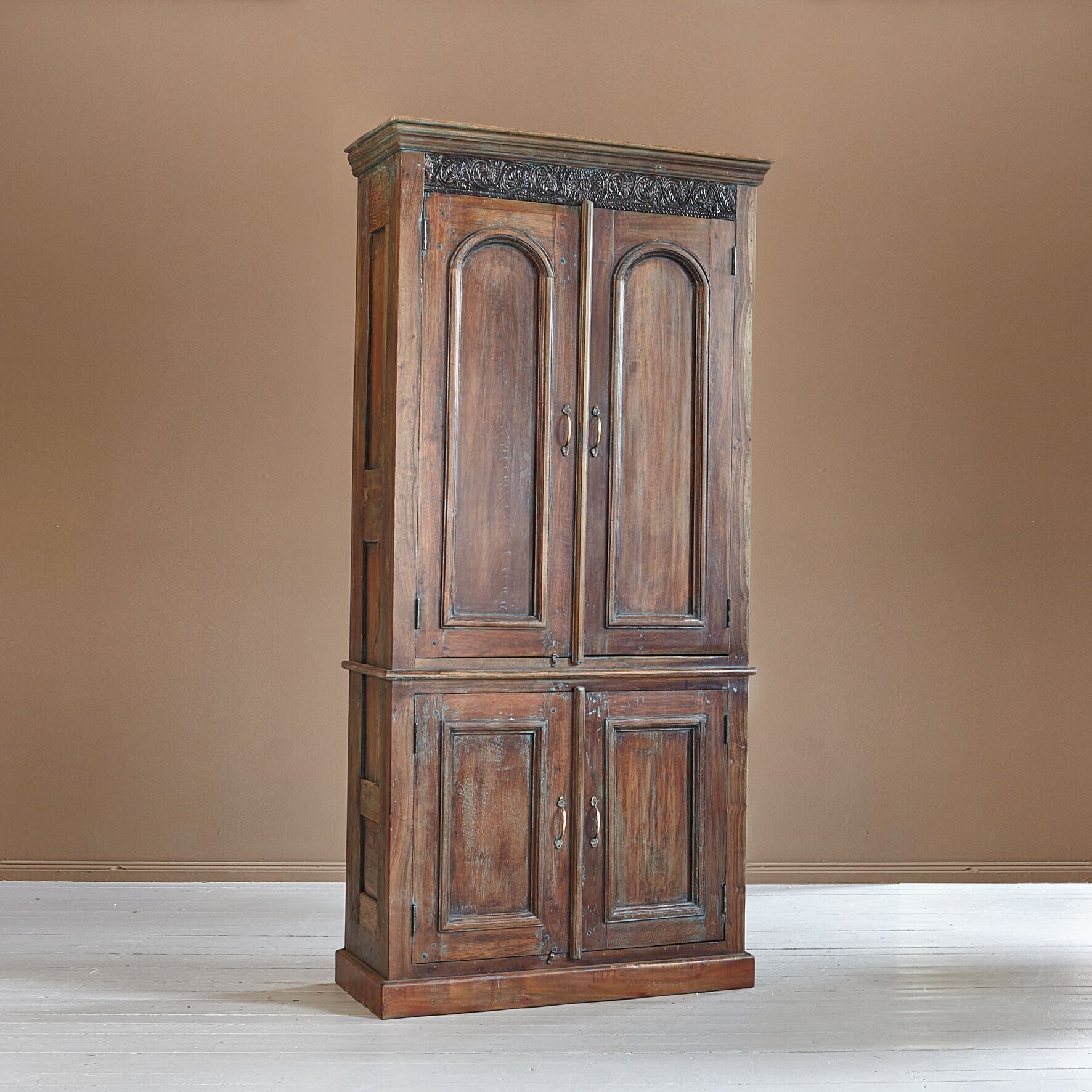 Wooden wardrobe with intricate carvings on a beige wall
