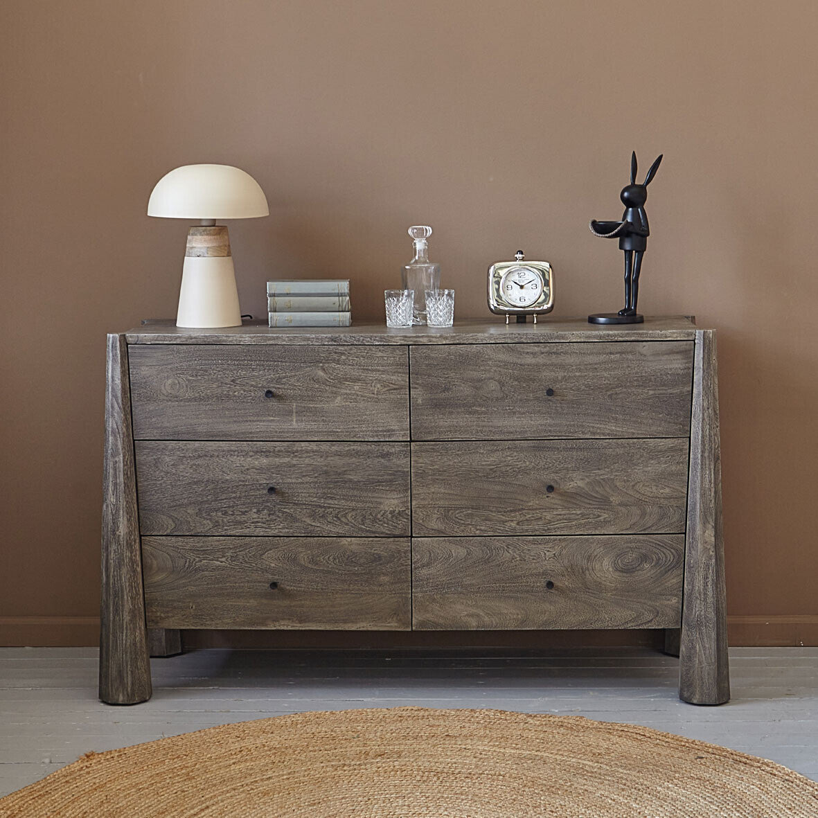 Wooden dresser with decorative items against a brown wall