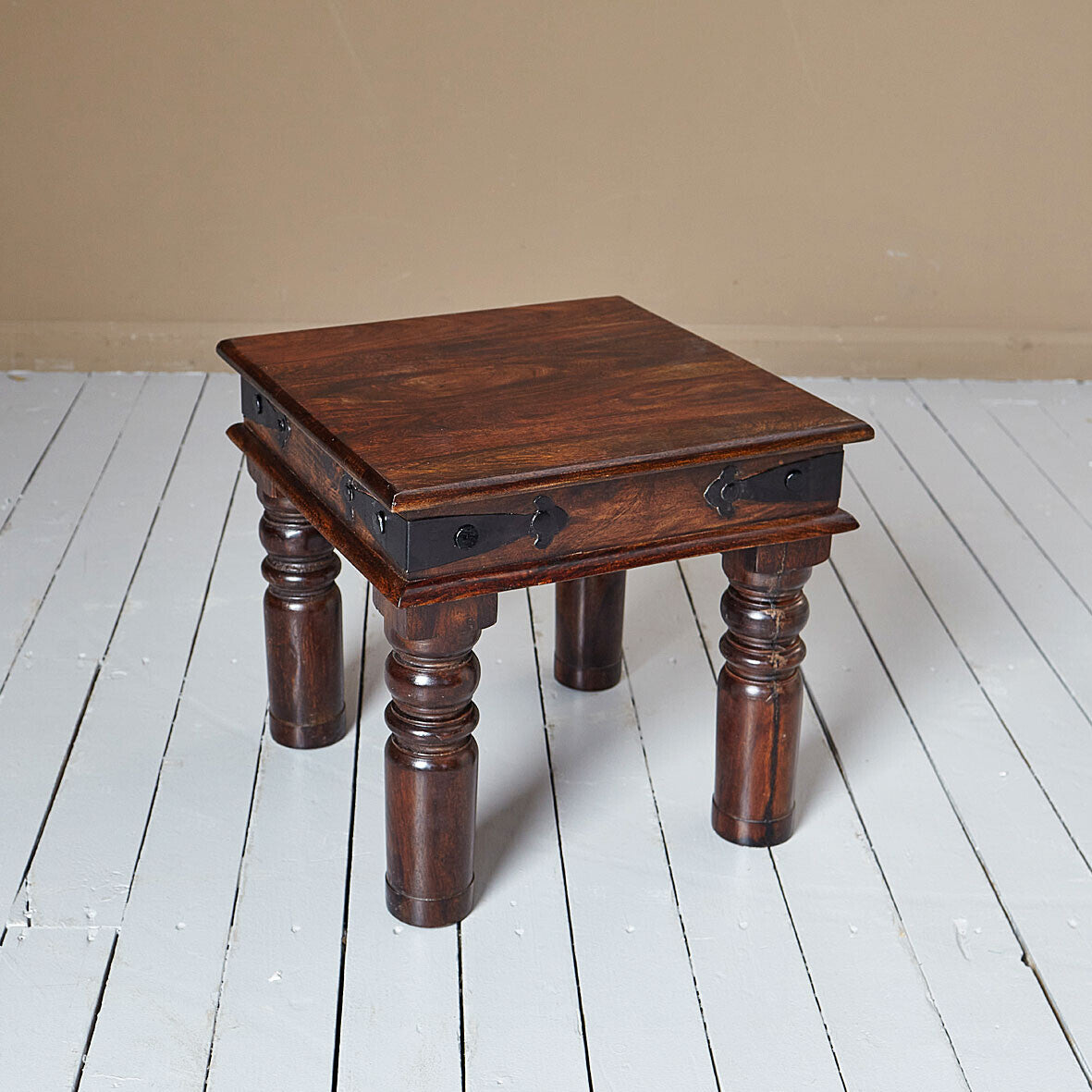 Wooden side table with dark brown finish on a white wooden floor.