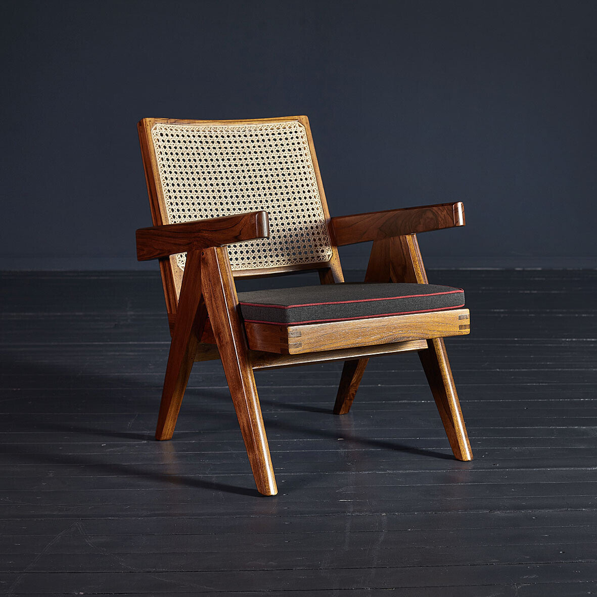 Wooden armchair with wicker backrest on a dark floor and background