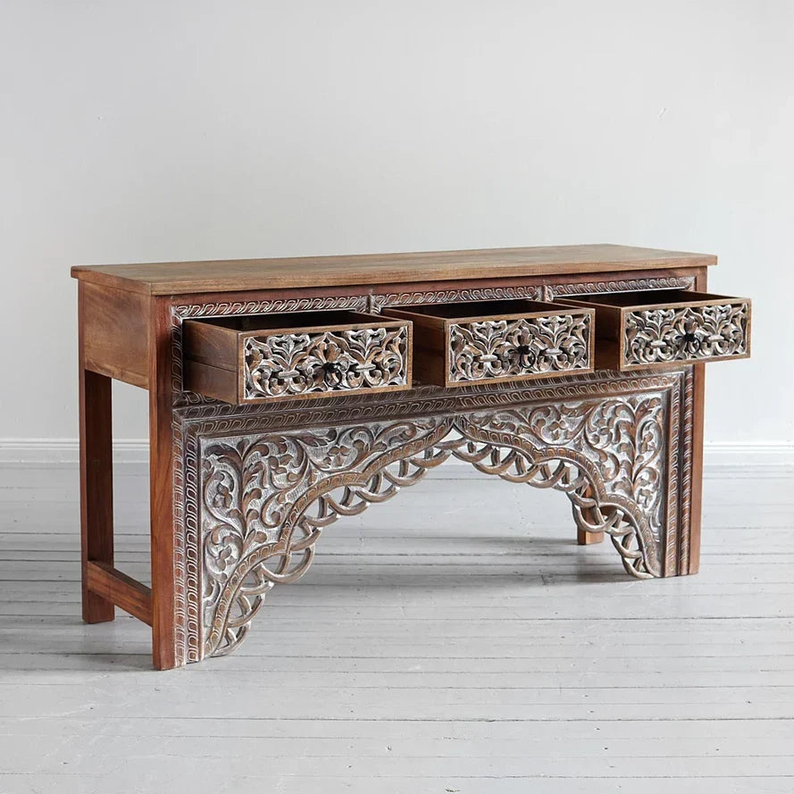 Wooden console table with intricate carvings on a light gray background