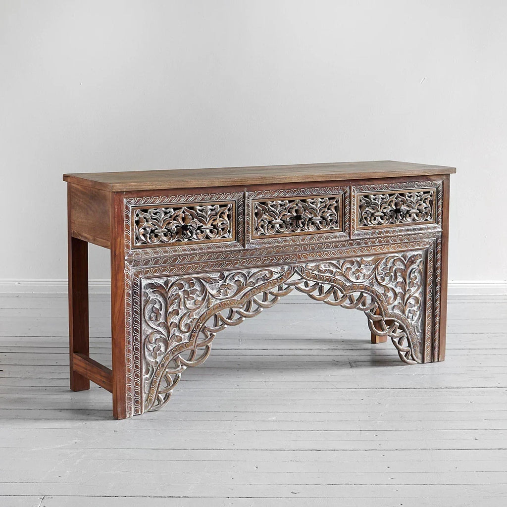 Wooden console table with intricate carvings on a light gray background