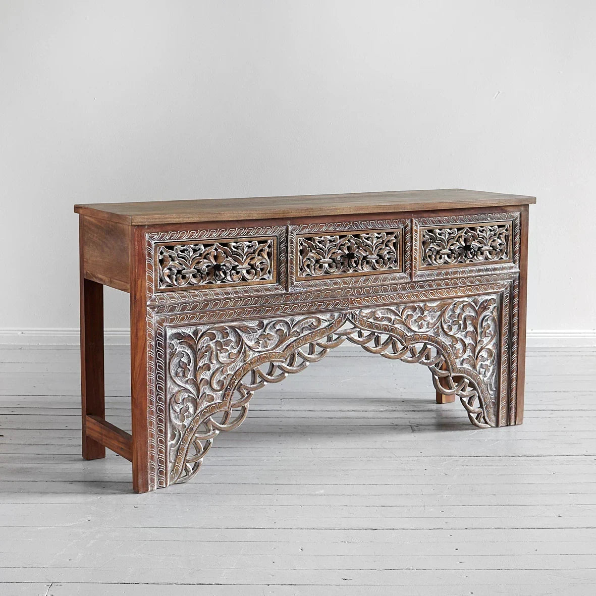 Wooden console table with intricate carvings on a light gray background
