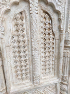 Close‑up of brass‑worked accents on hand‑carved mango wood vintage window frame.

