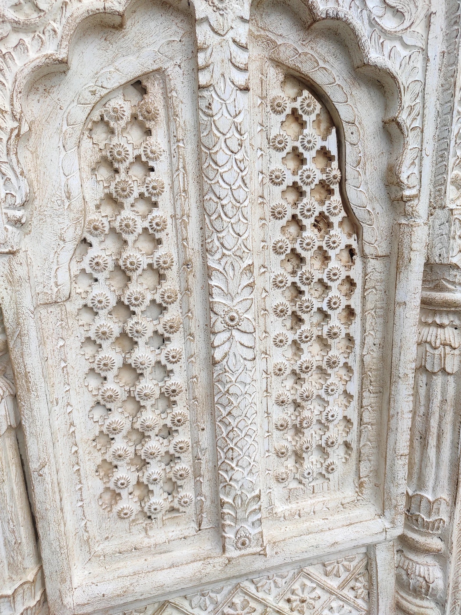 Close‑up of brass‑worked accents on hand‑carved mango wood vintage window frame.

