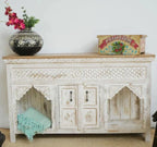 Decorative wooden sideboard with floral arrangement and vintage box on a plain background