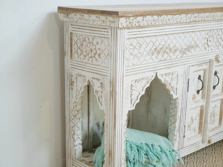 Decorative wooden cabinet with intricate carvings on a white wall.
