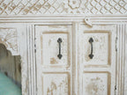 Vintage wooden cabinet with decorative carvings and black metal handles.