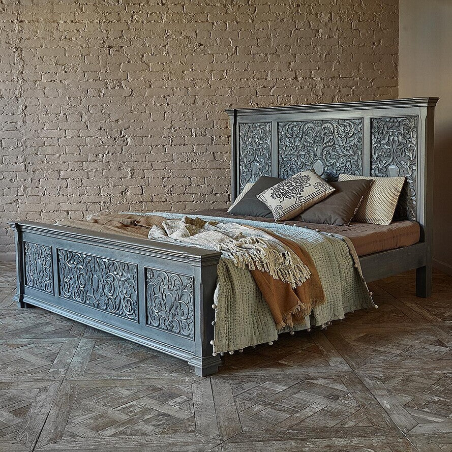 Decorative bed with intricate carvings against a brick wall.