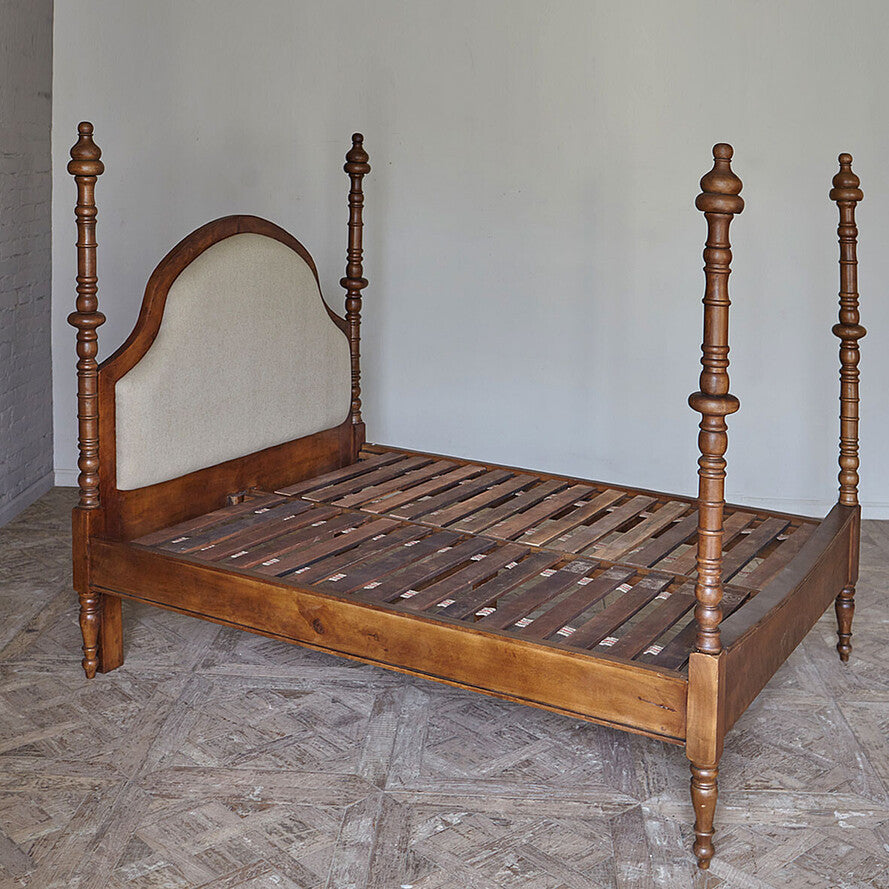Wooden bed frame with spindle design on a herringbone floor.