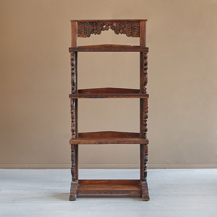 Wooden etagere with intricate carvings on a plain background