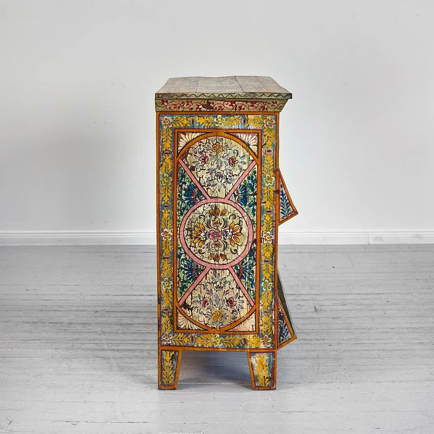 Decorative side table with floral patterns on a white floor and wall