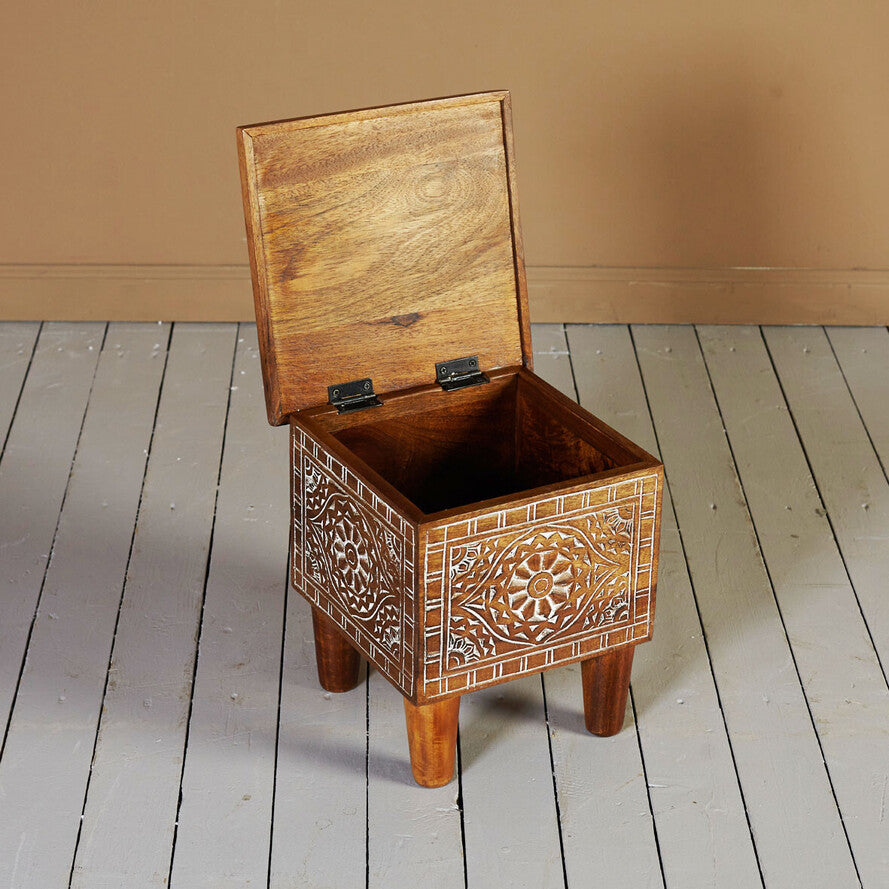 Wooden stool with intricate carvings on a wooden floor