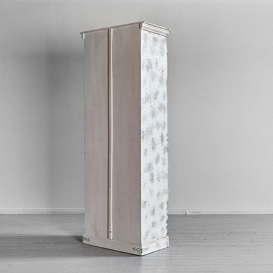 Tall, narrow cabinet with textured surface against a plain wall.