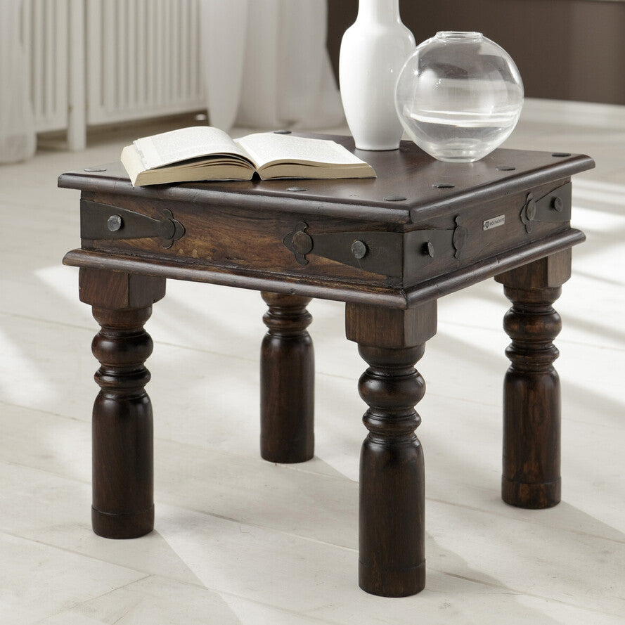 Wooden side table with books and decorative items on a light wooden floor.