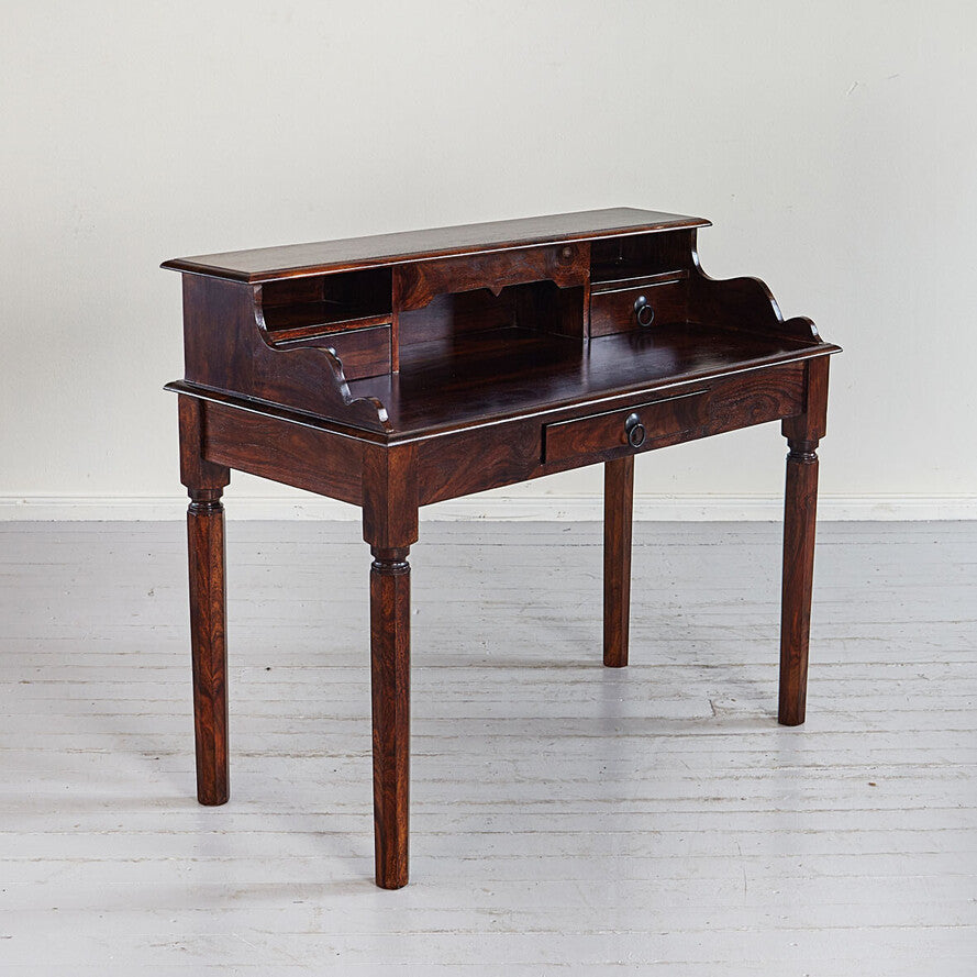Wooden desk with drawers on a white floor and light gray wall