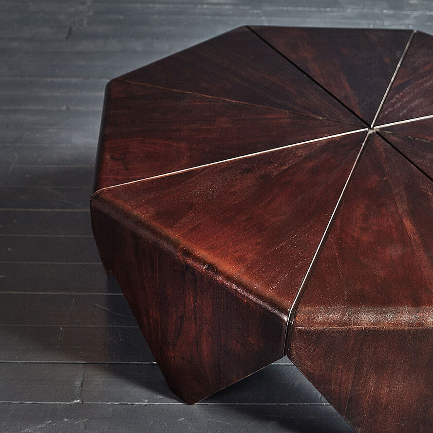 Hexagonal wooden stool with a dark finish on a gray floor.