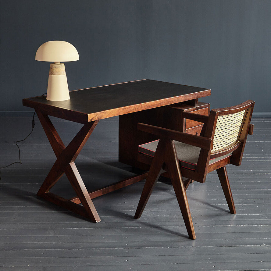 Wooden table with two chairs and a lamp on a dark gray floor and background