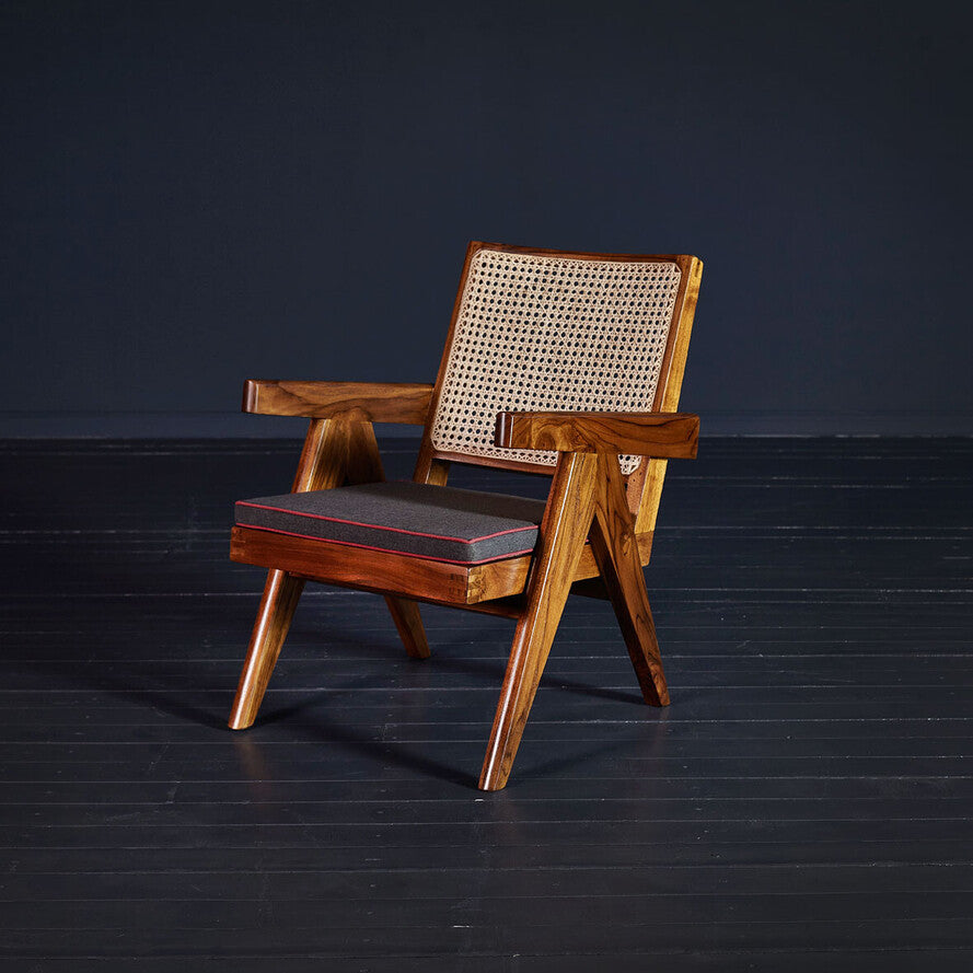 Wooden armchair with woven backrest and cushion on a dark floor and background