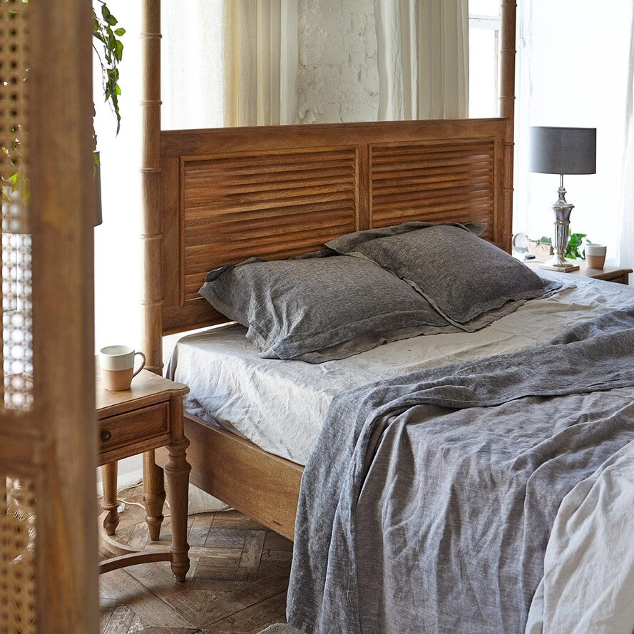 Wooden bed with gray bedding in a bright bedroom