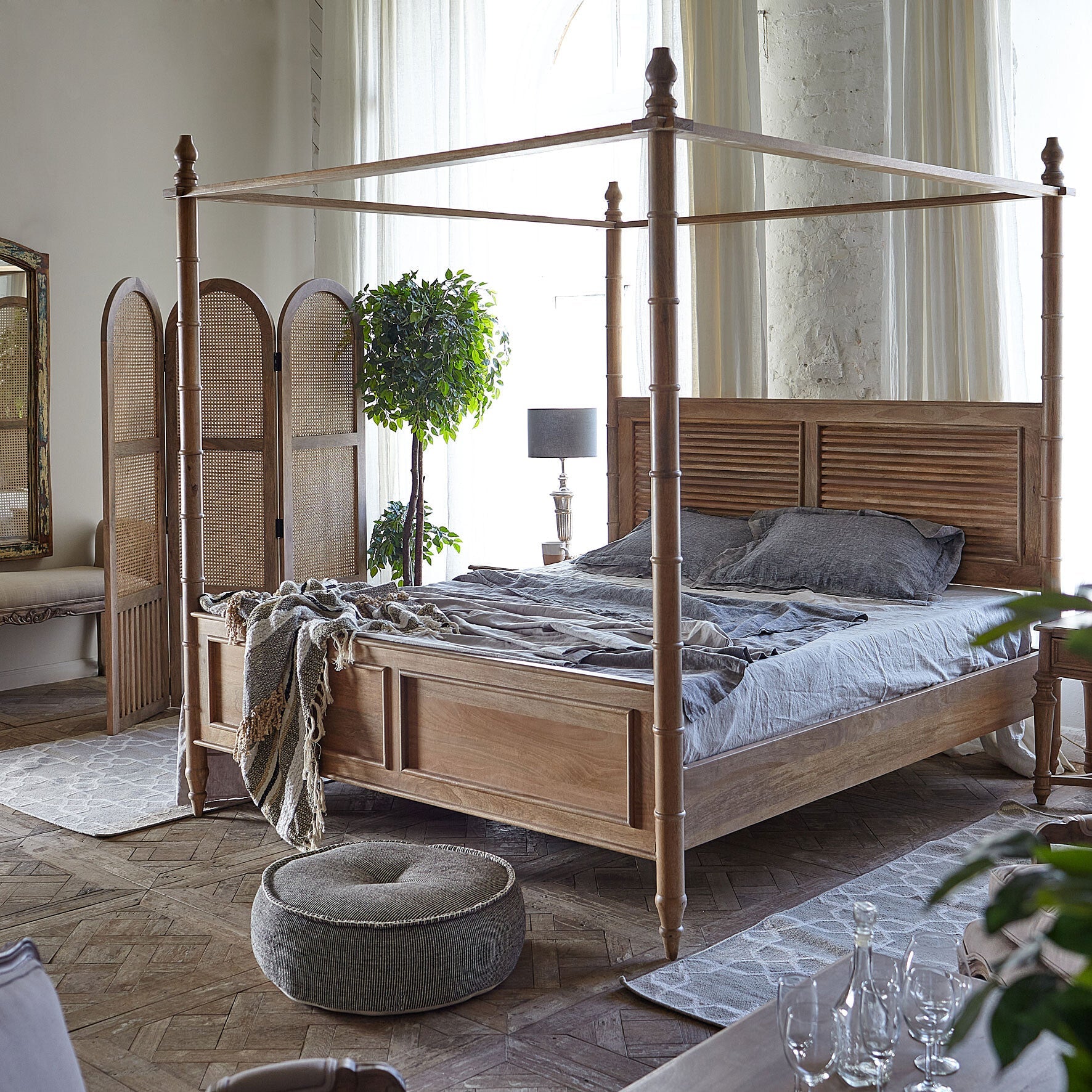 Wooden canopy bed in a bedroom with a rug and plant
