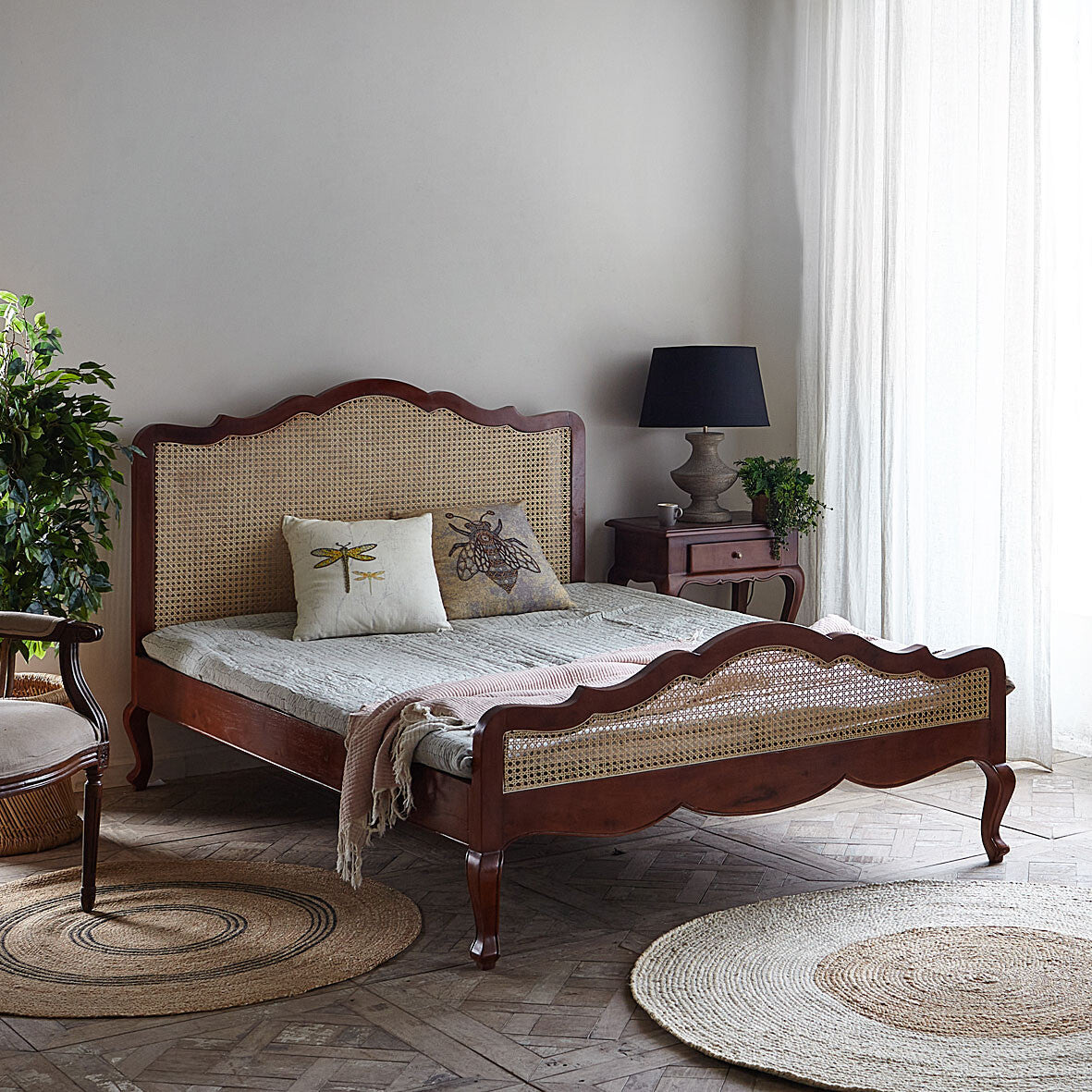 Bedroom with a wooden bed featuring a wicker headboard and footboard, surrounded by decor elements.