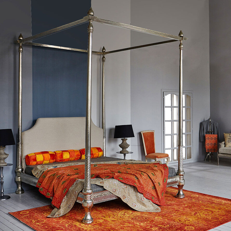 Decorative four-poster bed with ornate canopy in a stylish room.