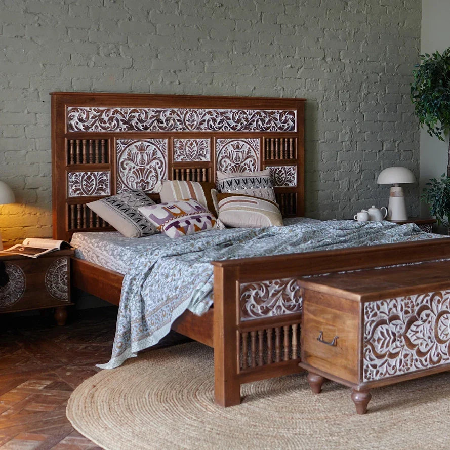 Wooden bed with intricate carvings in a bedroom setting.
