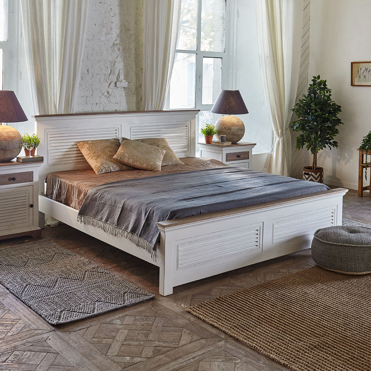 White wooden bed in a bedroom with decorative pillows and lamps.