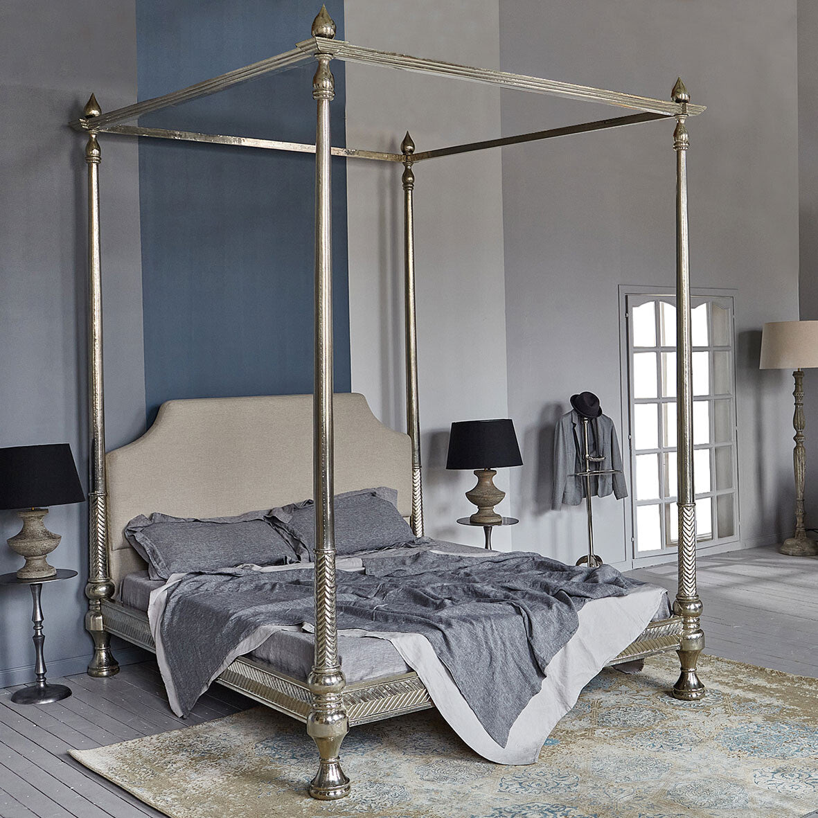 Silver four-poster bed in a bedroom with gray walls and a rug.