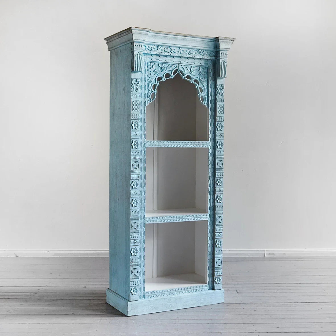 Decorative turquoise cabinet with intricate carvings on a white background