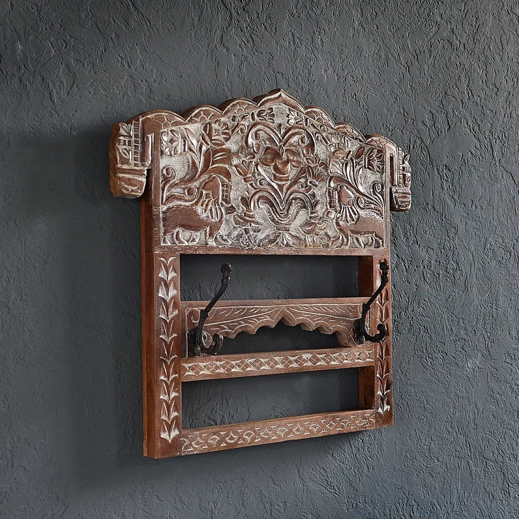 Decorative wooden wall shelf with intricate carvings on a dark gray wall.