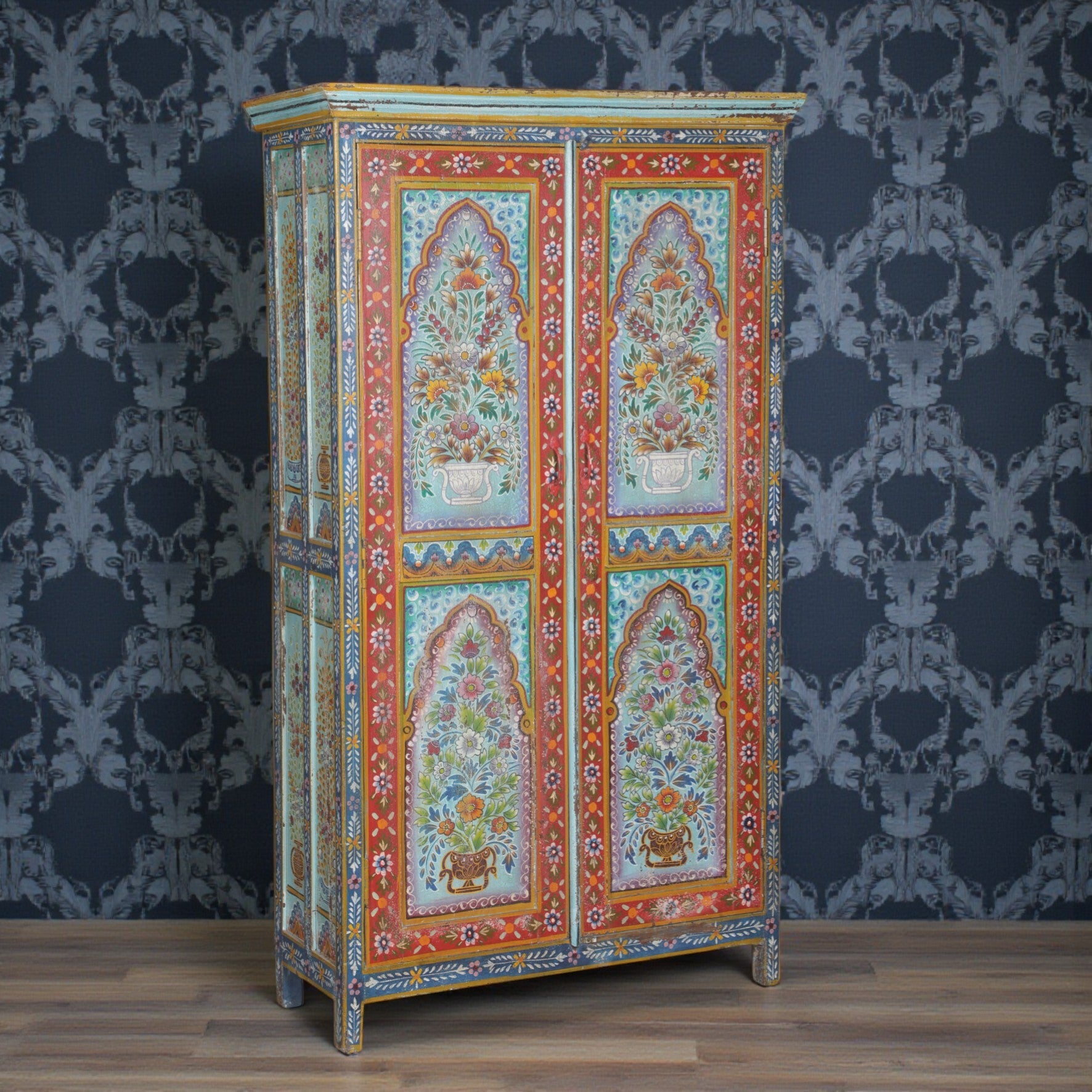 Decorative cabinet with floral patterns against a patterned wall.